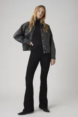 Jean de tiro alto con corte acampanado (flare), en color negro. Presenta un diseño clásico de cinco bolsillos y cierre frontal con botón y cremallera.