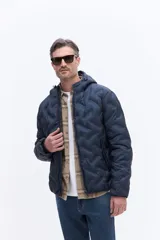 Campera de nylon matelaseada con diseño de costuras en zigzag, capucha integrada y cierre frontal. Presenta un ajuste regular y cómodo, ideal para media estación.