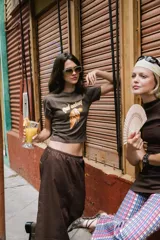 Remera corta de algodón color marrón, con estampado frontal de un cucurucho de helado derritiéndose y la frase "Qué calor!".