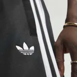 Pantalón deportivo adidas de corte recto, color negro con las clásicas tres tiras blancas a lo largo de los laterales y el logo del trébol bordado en la pierna. Cuenta con cintura elástica.