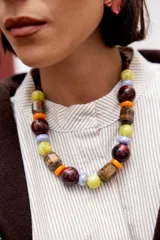 Collar corto de diseño llamativo compuesto por una mezcla de cuentas XL de diversas formas y materiales, incluyendo piedras ojo de tigre, cristales checos, cuentas de cerámica y acrílico en tonos multicolor. Cuenta con cadena de ajuste y cierre de gancho.