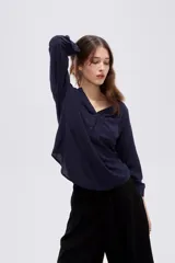 Blusa de viscosa color beige con cuello en V, cierre parcial de botones frontales, bolsillo en el pecho y mangas 3/4.