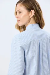 Camisa rayada de manga larga, confeccionada en algodón, con cuello mao y cierre frontal de botones.
