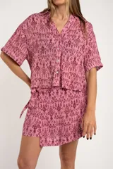 Short pollera color rosa con estampado abstracto en tonos borgoña y lazo lateral.