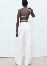 Pantalón de jean estilo wide leg, color blanco, con tiro bajo, cierre de botón y cremallera, y diseño de cinco bolsillos.