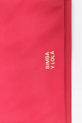 Billetera de estructura blanda confeccionada en nylon negro, con cierre de cremallera superior y bolsillo frontal con cierre. Presenta logo metálico dorado en el frente.