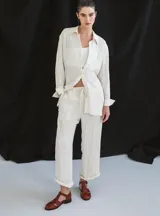 Sandalia cerrada tipo pescador, color blanco o hueso brillante, con tiras entrecruzadas en el empeine y cierre de hebilla ajustable en el lateral. Posee suela y taco bajo de color negro.