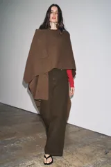 Capa de punto color marrón, con escote en V, mangas cortas y bolsillos de plastrón en el delantero. El ruedo tiene un corte asimétrico.