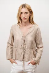 Chaqueta ligera de manga larga en color azul, con escote en V y cierre frontal mediante dos lazos ajustables. Presenta un diseño fluido con textura sutil y corte recto.