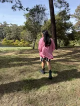 Camisa oversize de fibrana color rosa con botones rojos en forma de corazón y mangas largas con ajuste en los puños.