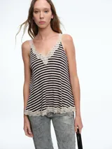 Top de tirantes con diseño a rayas horizontales en blanco y negro, confeccionado con terminaciones de encaje en el escote y en el ruedo.
