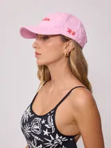 Gorra de lona color crema con visera celeste. Presenta bordado frontal en hilo azul claro con el texto "Rusty Tribe" y un pequeño diseño de flores.