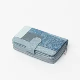 Billetera de mujer confeccionada en tela denim con diseño patchwork en tonos celestes y azules, cierre perimetral con cremallera y solapa frontal con broche magnético.