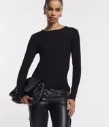 Suéter de punto color rosado, con cuello barco, mangas largas y puños con botones decorativos. El dobladillo también es acanalado.