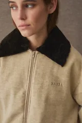 Campera bomber de paño color azul marino, con cuello de piel sintética en color marrón desmontable, cierre frontal y puños elásticos. Presenta logo bordado en el frente y bolsillos laterales.