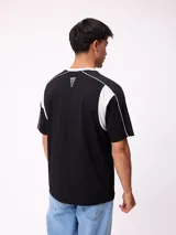 Remera de corte holgado en color negro con detalles en blanco en el cuello y paneles laterales. Presenta logo de la marca estampado en el centro del pecho.