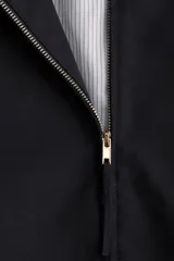 Campera bomber negra con cuello elevado, cierre frontal bidireccional y bolsillos laterales discretos. Cuenta con puños y dobladillo elásticos.
