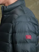 Campera puffer de plumas en color azul marino, con cierre frontal, cuello alto y diseño acolchado horizontal.