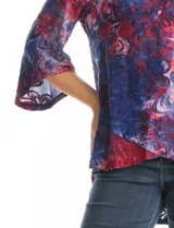 Blusa Ruby Rd. de corte holgado con diseño texturizado y estampado floral en tonos azul y bordó. Presenta cuello redondo con escote tipo keyhole y detalle metálico, mangas tres cuartos amplias y dobladillo asimétrico.