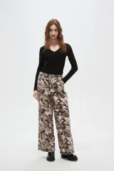 Pantalon de corte baggy con cintura media y bolsillos laterales. Presenta un estampado abstracto tipo camuflado en tonos tierra.