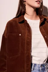 Sobrecamisa de pana color rojo, con cierre frontal de botones, bolsillos delanteros con solapa y ruedo desflecado.