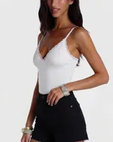 Body blanco con escote en V profundo y detalles de puntilla en los bordes, tirantes finos regulables y diseño ajustado.