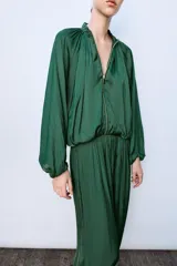 Pantalón de tiro medio confeccionado en tejido satinado verde, con diseño bombacho y bajos acabados en puño elástico. Cuenta con cierre lateral con cremallera oculta en costura.