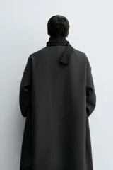 Trench de corte oversized confeccionado en tejido compacto con mezcla de lana. Presenta cuello solapa, cierre frontal con botonadura, mangas largas y bolsillos de vivo en la cadera.