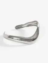 Pulsera rígida de acero quirúrgico hipoalergénico, color plateado, con diseño ondulado.