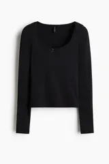 Remera negra de manga larga, corte ajustado y corto (cropped), confeccionada en tejido de punto acanalado. Presenta un escote redondo ribeteado con encaje y un pequeño lazo de satén en el centro del escote.