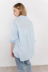 Camisa celeste de algodón liviano con bordado calado tipo broderie, manga larga con puño angosto y botones al frente.