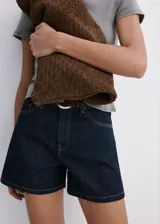 Short de denim azul oscuro con diseño de cinco bolsillos, tiro medio y cierre frontal de cremallera y botón.
