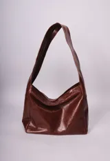 Bolso tipo hobo de cuero negro con correa ancha para el hombro.