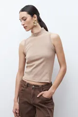Top sin mangas de tejido canalé en color blanco, con cuello alto tipo tortuga y ajuste al cuerpo.