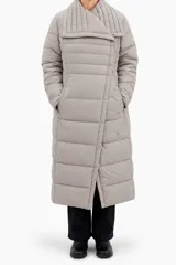 Campera larga puffer color gris, matelaseada con diseño horizontal, cuello envolvente amplio y cierre cruzado con botones a presión.