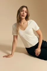 Remera de manga corta en tejido acanalado, con escote en V y detalles de puntilla en el borde del escote y en las mangas. Presenta un ajuste entallado al cuerpo.