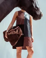 Bolso de mano tipo duffel de gran capacidad, confeccionado en gamuza color chocolate. Presenta doble asa corta superior y correa larga ajustable para llevar al hombro o cruzada.