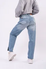 Jean mom fit de tiro alto en color azul claro con lavado vintage. Presenta un corte relajado y tajos laterales en el ruedo de los tobillos.