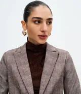 Blazer femenino de corte acinturado confeccionado en tejido punto roma con estampado de cuadros. Presenta solapas estructuradas, cierre frontal de doble botonadura, mangas con botones decorativos y recortes traseros.