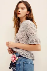 Sweater gris de tejido calado, con cuello redondo y mangas cortas abullonadas con puños elastizados.