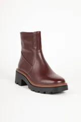 Bota corta de cuero sintético color negro, con punta redonda, cierre lateral y suela tipo tractor con plataforma de 6 cm.