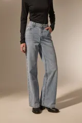 Pantalon de jean de corte recto y tiro medio, con detalle de ojales metálicos a lo largo de la costura lateral externa.