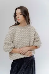 Buzo de punto grueso con diseño bicolor en patrón geométrico, de calce holgado y mangas largas.