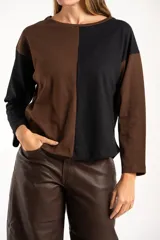 Sweater de algodón con diseño bicolor en bloques, combinando tonos marrón y negro. Presenta cuello redondo, mangas largas y una textura acanalada.