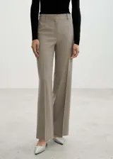 Pantalon de vestir corte wide leg color beige, con tiro medio, trabillas para cinturón y detalle de pinzas frontales. Cuenta con bolsillos laterales y cierre oculto con botón, gancho y cremallera.