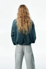 Chaqueta de punto pesado con escote redondo, cierre frontal y bolsillos laterales insertados. Diseño oversized con hombros caídos, puños y bajo elásticos.