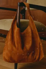 Cartera tipo tote de tamaño mediano, confeccionada en cuero agamuzado. Presenta un diseño simple y amplio con una sola asa integrada y bolsillo interior.