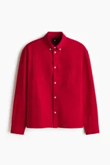 Camisa en algodón Oxford de color rojo con cuello americano, bolsillo superior abierto, mangas largas con puños abotonados y corte relajado.