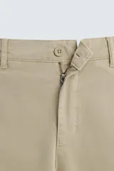 Pantalón chino de corte ajustado, color beige, con bolsillos laterales y bolsillos traseros de vivo. Cuenta con cierre frontal de cremallera y botón.