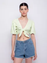 Top corto de color verde claro con estampado a cuadros blancos, escote en V y mangas cortas abullonadas. Se ata en el frente con un nudo.